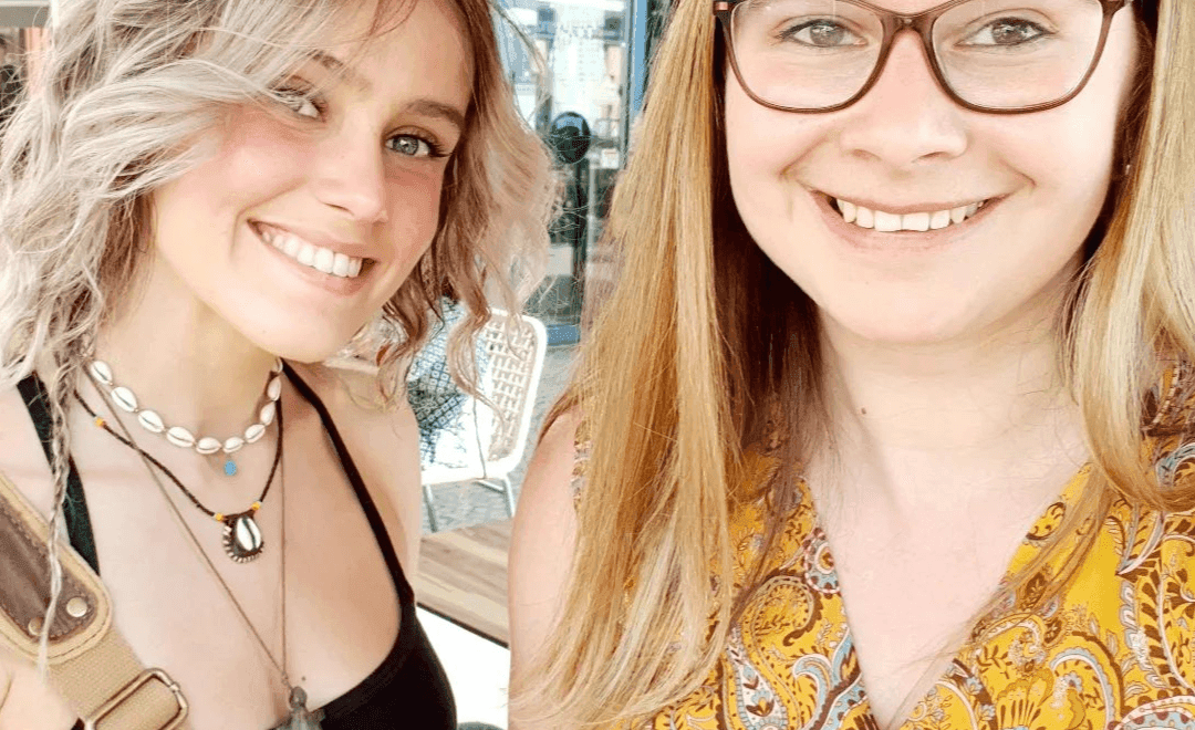 Deux filles souriantes se tiennent par les épaules.